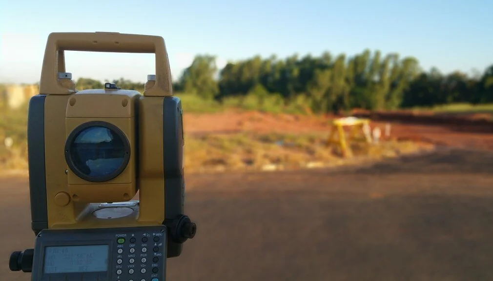 Surveying instrument positioned beside a rural road