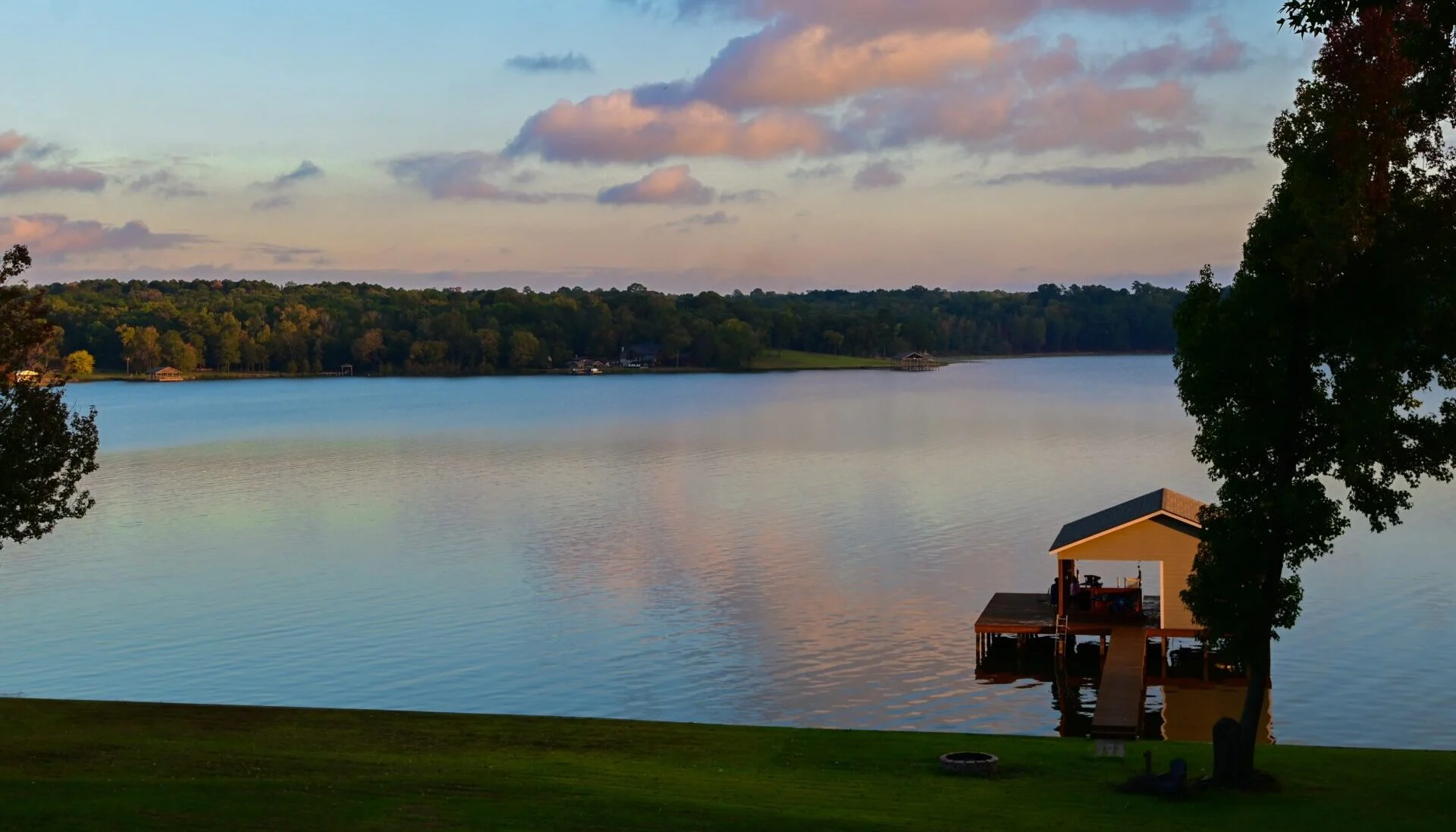 Person seated beside a lake at sunset