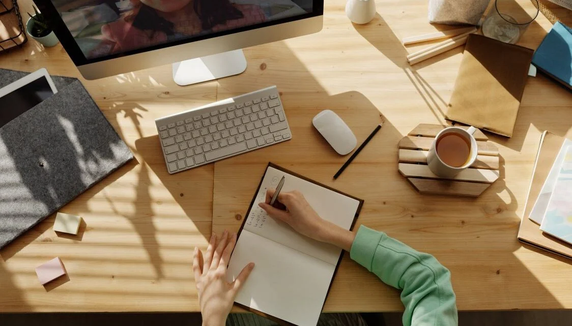 Overhead view of a desk with a tablet, notebook, and coffee cup
